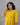 Woman wearing a yellow dress against a gray background