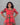 Woman wearing a red and green patterned dress against a gray background