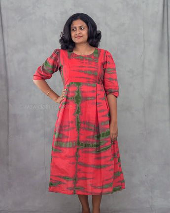 Woman wearing a red and green patterned dress against a gray background