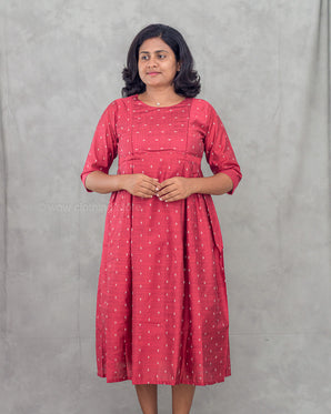 Woman wearing a red dress with white patterns against a gray background