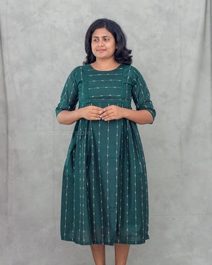 Woman wearing a green feeding top with white patterns against a gray background