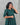 Woman wearing a green maternity top with a subtle pattern against a gray background