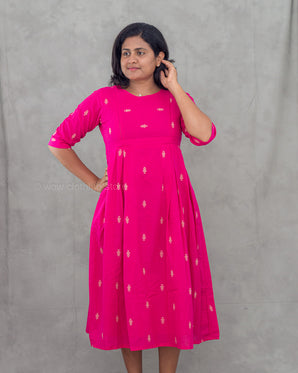 Woman wearing a bright pink feeding top with white patterns against a gray background