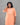 Woman wearing an orange kurta with white embroidery against a gray background