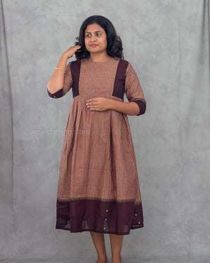 Woman wearing a brown and purple dress against a gray background