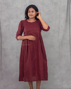 Woman wearing a maroon checkered dress against a gray background