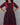 Woman wearing a wine red dress with red accents against a gray background