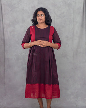Woman wearing a wine red dress against a gray background