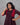Woman wearing a wine red dress against a gray background