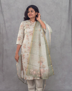 Woman wearing a floral kurti with a green dupatta against a gray background
