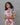 Woman wearing a colorful floral dress against a gray background