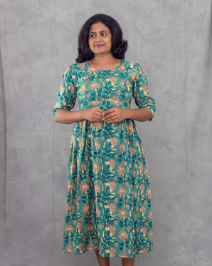 Woman wearing a green floral dress against a gray background