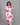 Woman wearing a white dress with pink floral patterns against a gray background