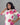 Woman wearing a white top with pink floral patterns against a gray background