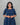 Woman wearing a blue dress with a pattern against a gray background