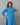 Woman wearing a blue patterned kurta against a gray background