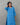 Woman wearing a blue patterned dress against a gray background