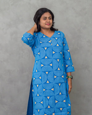 Woman wearing a blue patterned dress against a gray background