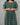 Woman wearing a green patterned dress against a gray background