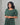Woman wearing a green patterned nursing top against a gray background