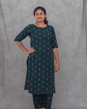 Woman wearing a green jacwuard kurti with matching pants against a gray background