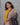 Woman wearing a yellow top and black and beige kalamkari dupatta against a gray background