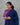 Woman wearing a blue and pink traditional outfit against a gray background