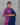 Woman wearing a purple and blue traditional outfit against a gray background