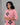 Woman wearing a pink traditional outfit with black patterns on a gray background