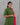 Woman wearing a green traditional outfit with a pink dupatta against a gray background