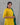 Woman wearing a yellow outfit with green accents against a gray background
