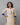 Woman wearing a cream kurta with blue sleeves against a gray background