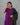 Woman wearing a purple top and black saree with gold border against a gray background