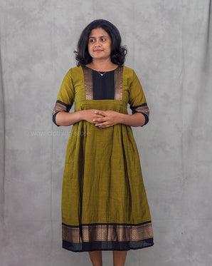 Woman wearing a green and black traditional dress against a gray background