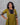 Woman wearing a green and black traditional outfit against a gray background
