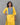 Woman wearing a yellow kurta with blue embroidery against a gray background