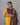 Woman wearing a yellow kurta with a patterned dark blue and brown dupatta against a gray background