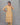 Woman wearing a yellow floral kurti with pants against a gray background
