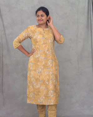 Woman wearing a yellow floral kurti with pants against a gray background
