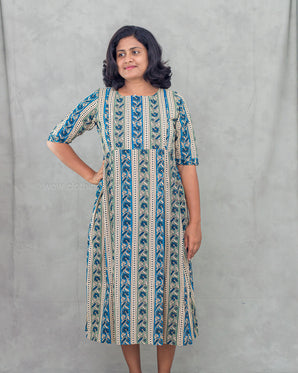 Woman wearing a blue patterned feeding dress against a gray background