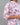 Person wearing a floral patterned shirt with pink and blue leaves on a gray background