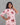 Woman wearing a pink dress with cherry pattern against a gray background