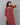 Woman wearing a maroon patterned kurti suit against a gray background