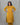 Woman wearing a mustard yellow kurta with floral embroidery against a gray background