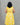 A women wearing yellow color cotton a-line kurti with back rope on a grey background