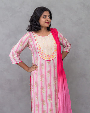 Woman wearing a pink and white kurti with a matching dupatta against a gray background