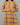 Person wearing a mustard yellow dress with brown pattern on a gray background