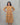 Woman wearing a mustard yellow maternity dress against a gray background