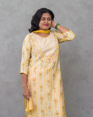 A women wearing yellow color printed modal kurti suit with plain bottom and a dual color dupatta on a grey background
