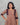 Woman wearing a brown striped feeding top with maroon straps against a gray background